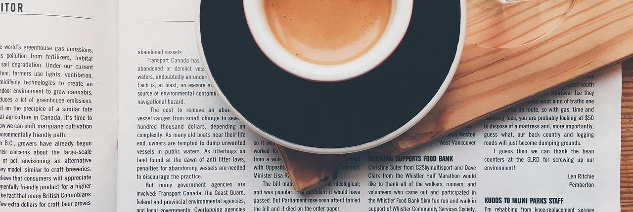 pubblicazioni-libera-universita-del-gioco Sopra ad una rivista c'è una tazzina di caffè e un bicchiere di vetro.