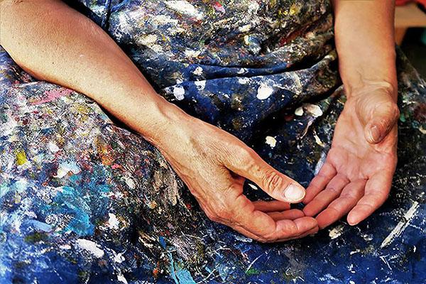La foto mostra due braccia femminili con le mani a riposo dopo un lavoro manuale.