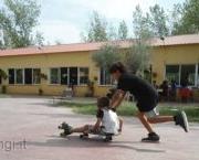 Foto di un bambino che spinge un altro bimbo seduto su un carrettino di legno.