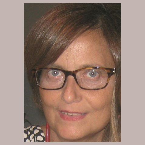 Una donna sulla sessantina, con gli occhiali e capelli lunghi, sciolti, sorridente.